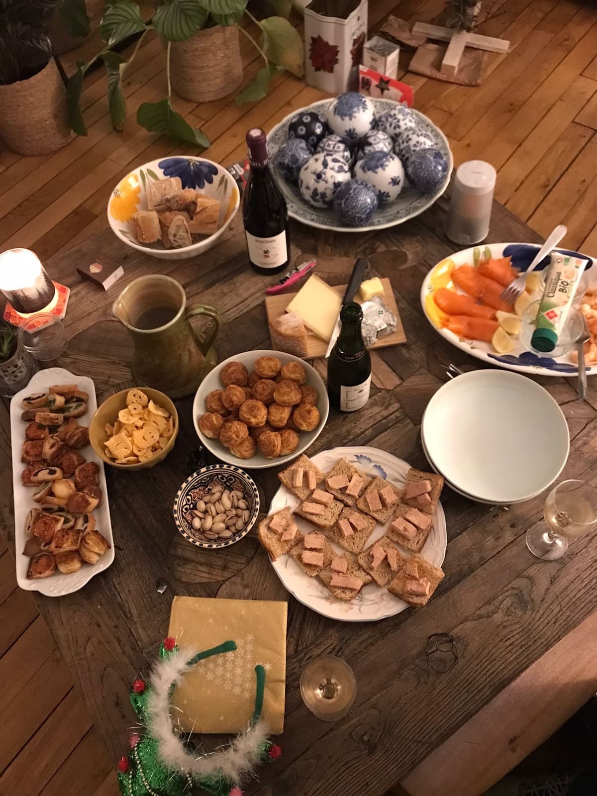 A crowded table of party food: canapes, cheese, smoked salmon, bread and wine.